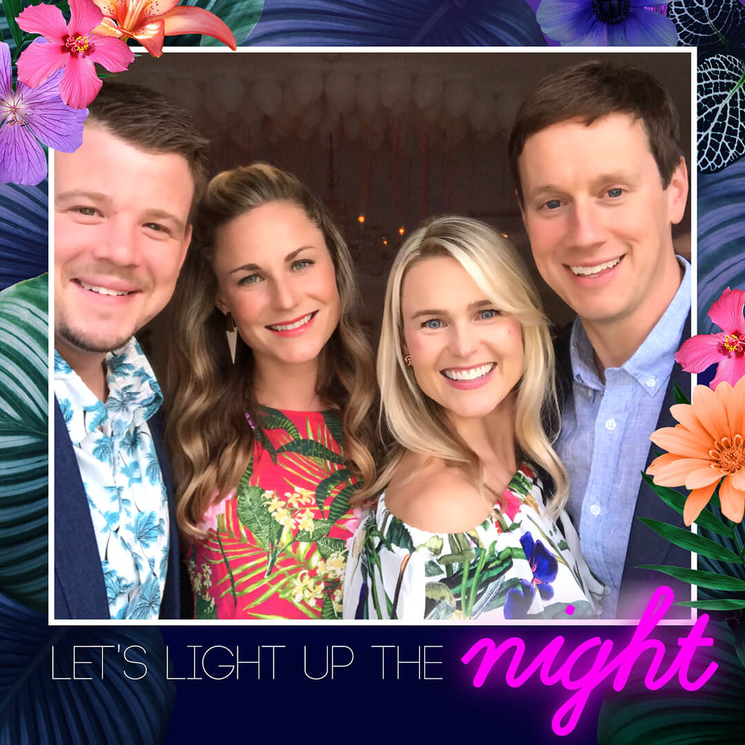 Four friends pose in a photo booth. A skin smoothing Glam Filter is applied. Caption under photo reads Let's Light up the Night and tropical flowers and plants make up the frame around the image.